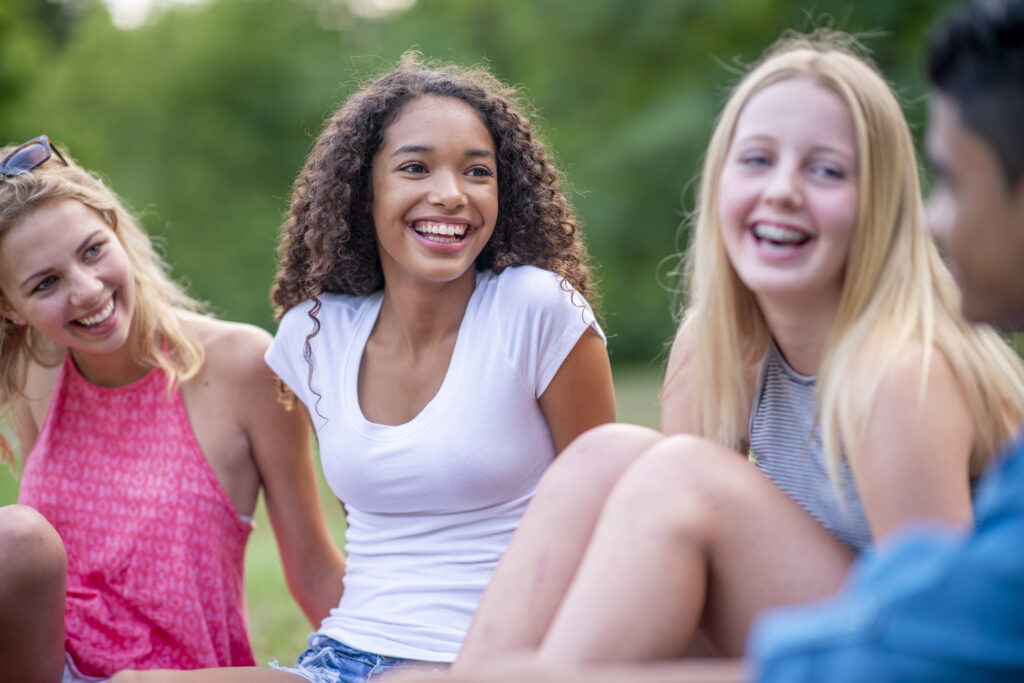 A small group of teens enjoys summer vacation hanging out at a park.