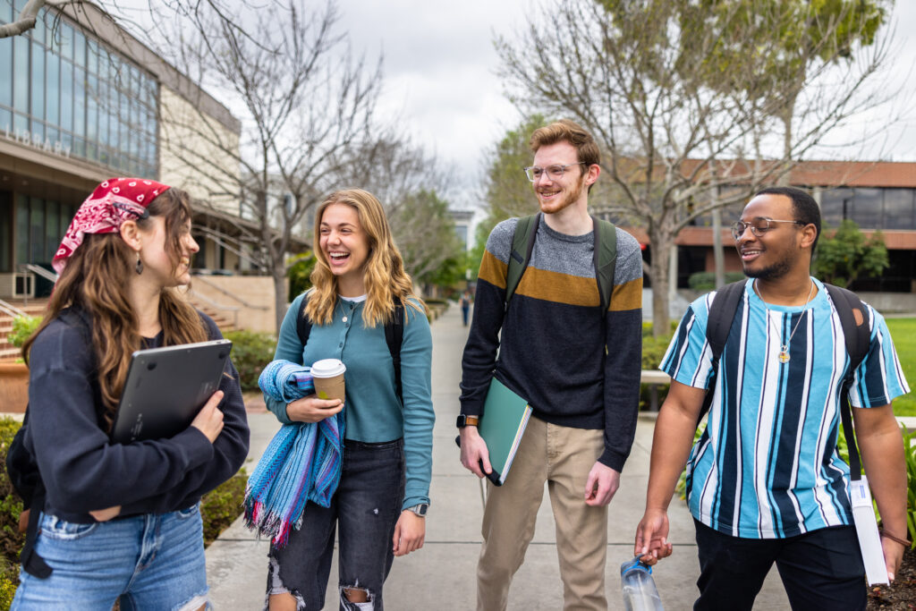 A group of students laughs as they enjoy they enjoy their first semester of college on campus.