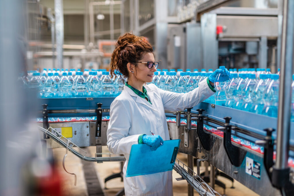 Young woman works at an advanced manufacturing plant bottle line.