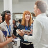 College students practice networking for internships with employer.