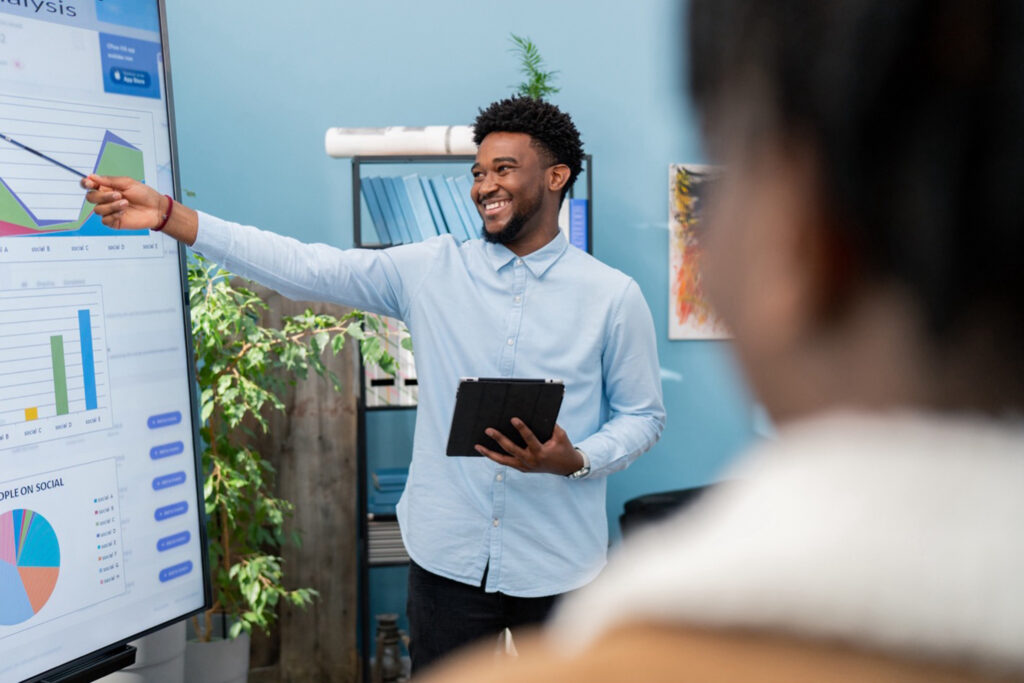 Man practices oral communication by presenting at a business meeting
